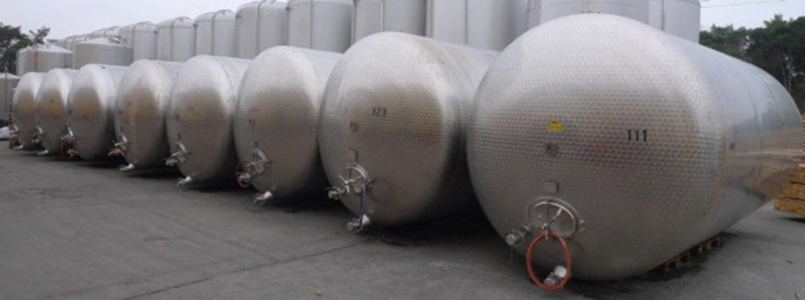 acht im Freien nebeneinander liegende, gebrauchte Edelstahl Druckbehälter, Volumen 25.250 Liter, im Lager der Firma Tank und Apparate Barth GmbH, Lebensmitteltanks aus VA