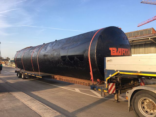 Schwarzer, bitumenisolierter, unterirdischer Regenwassertank der Firma Tank und Apparate Barth GmbH mit 100.000 Litern Volumen auf einem LKW liegend